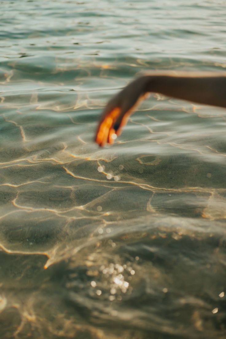 Mão tocando suavemente a água transparente ao sol